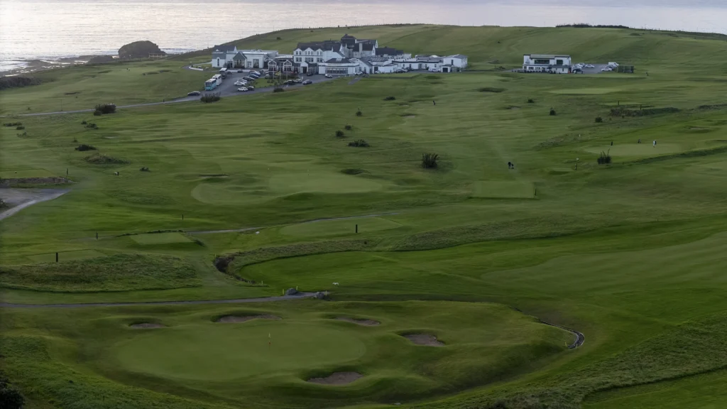 Bundoran Golf Club at dusk, with the clubhouse above the green and the sea in the background