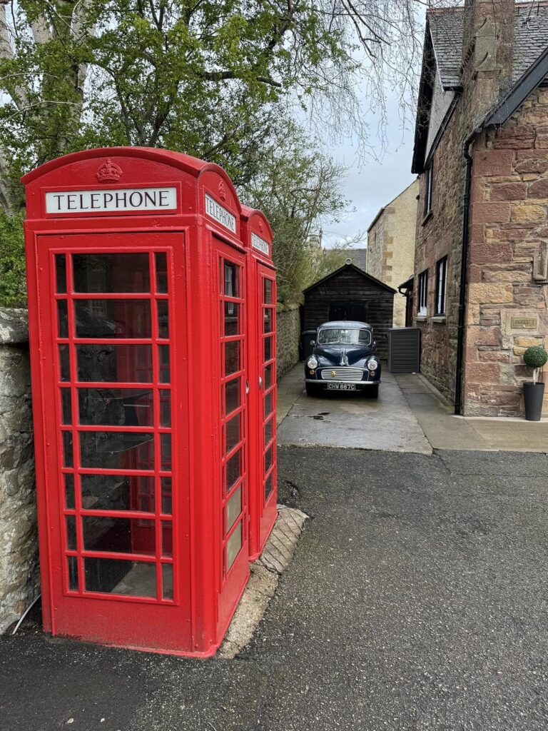 Red telephone boxes and a vintage Morris Minor on Castle Street in Dornoch