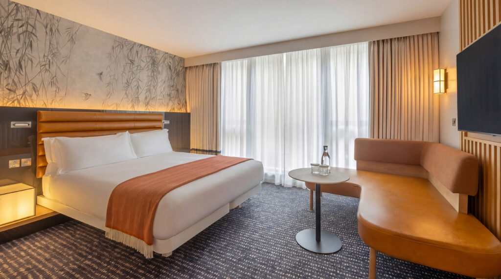 Deluxe room at The Morrison in Dublin with a double bed, curtained window and a leather sofa