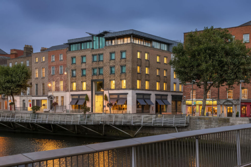 The Morrison hotel on the River Liffey in Dublin at dusk, with lit windows behind the quayside railing