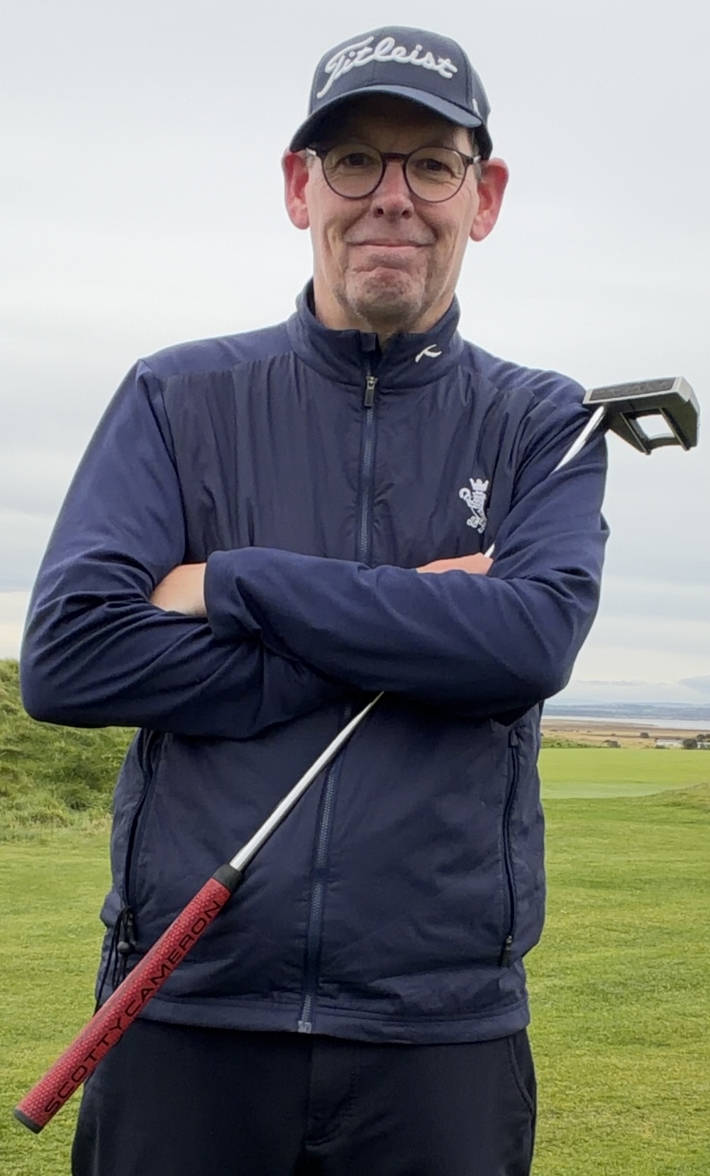 Joerg on a links course with his putter over his shoulder, smiling