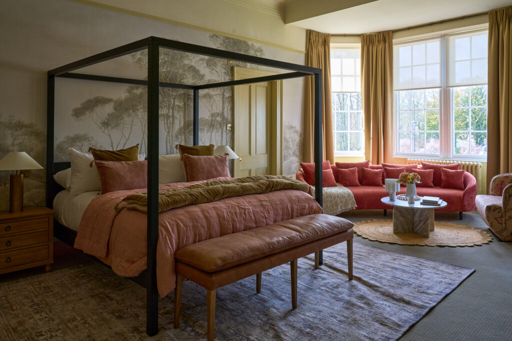 Manor room at Meldrum House with a four-poster bed, a coral sofa and tall bay windows